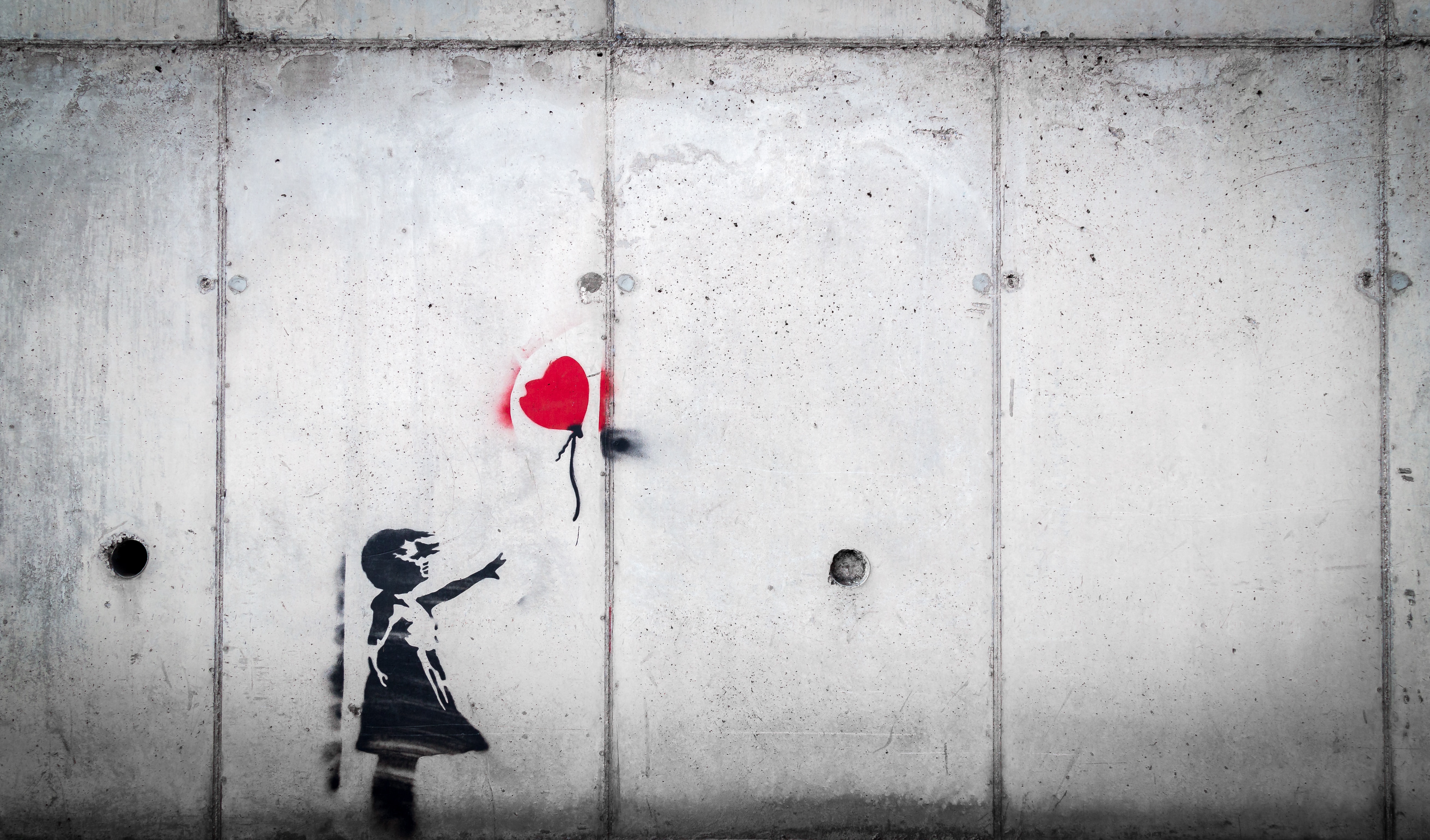 Image of a stenciled girl in black letting go of a red heart balloon